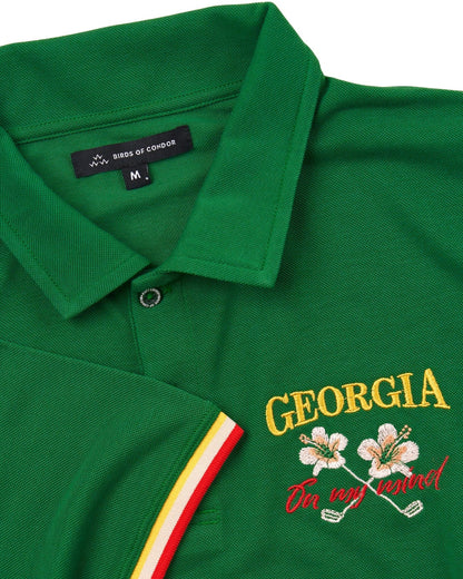 Detail of a green polo shirt with tri-colour sleeve cuffs and an embroidered Georgia logo.