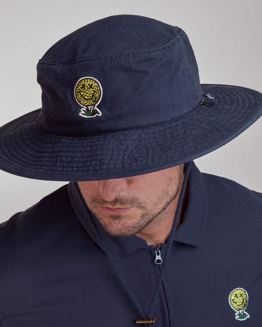 A man wearing a navy boonie hat with a yellow smiley golf ball graphic and a tonal drawcord.