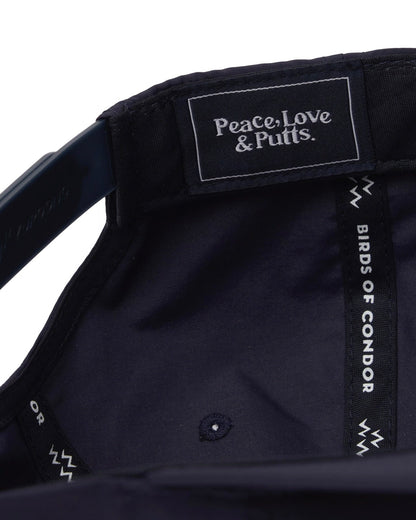 Detail of the interior of a navy cap, showing a branded label reading "Peace, Love & Putts."