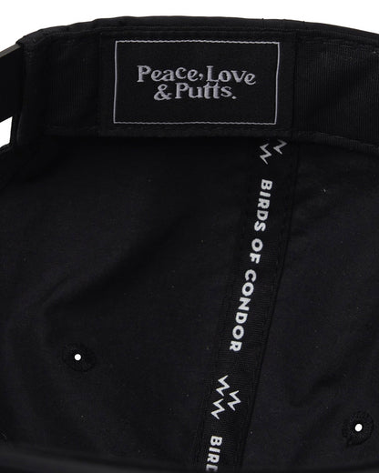 Detail of the interior of a black nylon cap showing the logo text Peace, Love & Putts on the inner taping.
