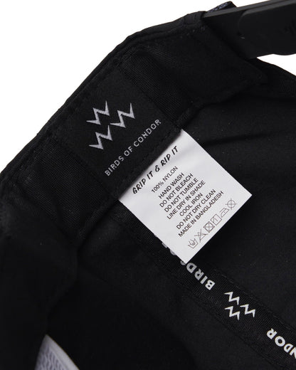Detail of the inside of a black cap, showing a brand tag and a care label.