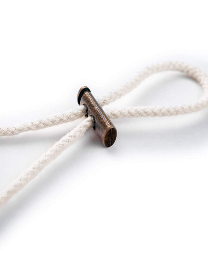 Detail of an off-white cotton boonie drawcord secured with a brass fastener.