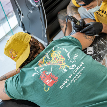 Back of a green t-shirt featuring a graphic of a pizza slice playing golf and white text.