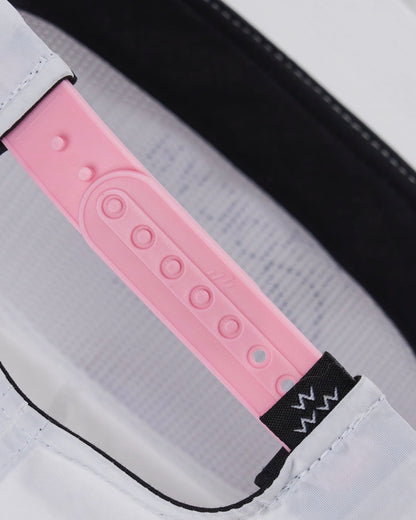 Detail of the pink plastic snapback closure on a white nylon cap with a black interior band.