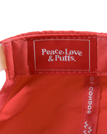 Detail of the blood orange nylon snapback interior, featuring a rectangular label reading Peace, Love & Putts.