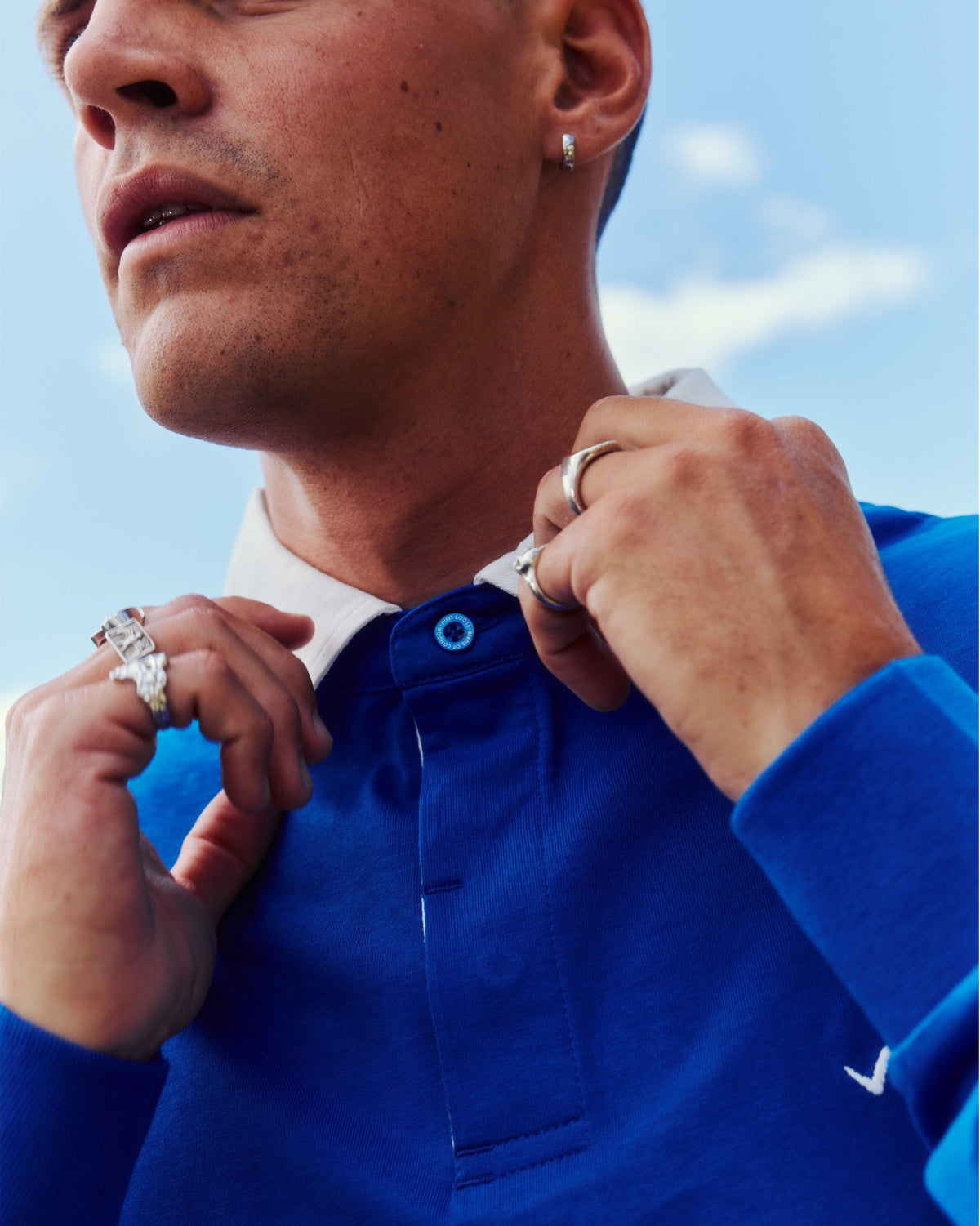 Detail of a blue sweater with a white collar and an embroidered placket.