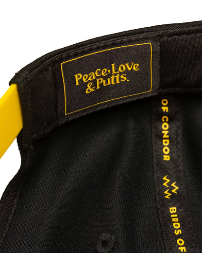 Detail of a black cap interior, featuring a yellow snap closure and text reading "Peace, Love & Putts."