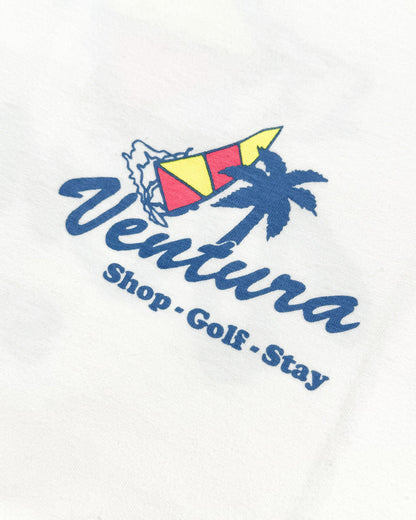Detail of a white t-shirt featuring a blue Ventura graphic with a palm tree, flag, and text.