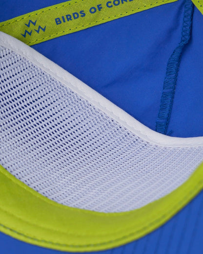 Detail of the interior white mesh and fluoro green taped seams inside the blue snapback cap.