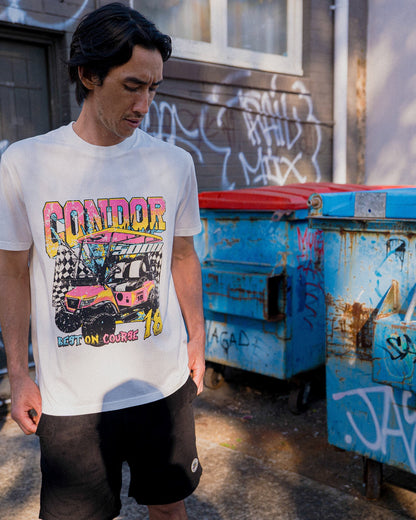 A man wearing a white t-shirt featuring a colourful retro golf cart graphic on the front.