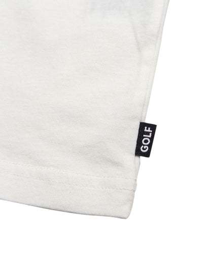 Detail of a white t-shirt featuring a small black woven tag on the hem with white text reading GOLF.