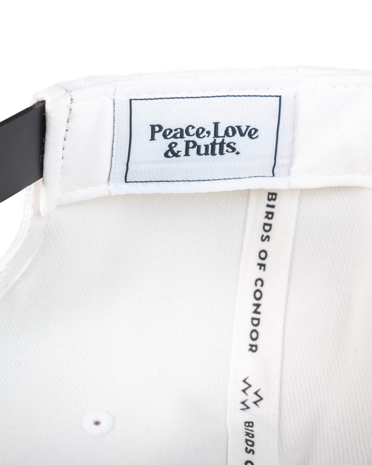 Detail of the white snapback interior showing a woven label reading Peace, Love & Putts.