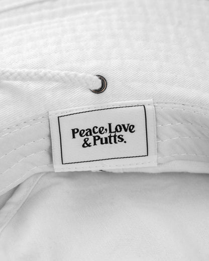 Detail of a white cotton canvas boonie featuring a tonal drawcord, brass fastener, and a label reading Peace, Love & Putts.
