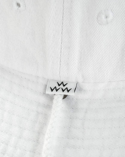 Detail of white cotton boonie featuring a small label with a black W motif and a drawstring.