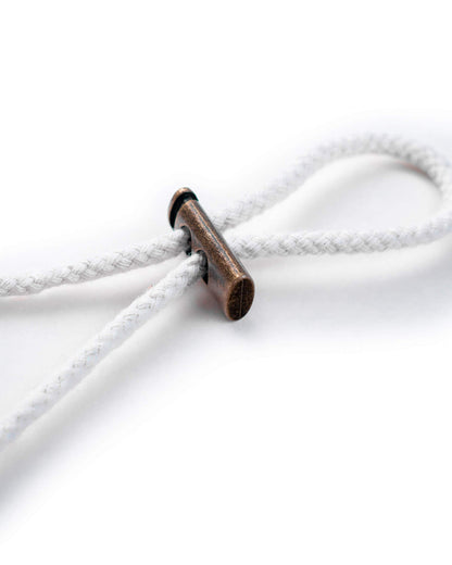 Detail of the white cotton boonie hat drawcord fastened with a brass toggle.