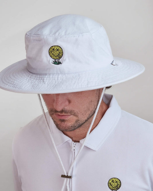 A man wearing a white cotton boonie hat featuring a yellow smiley face golf ball design on the front.