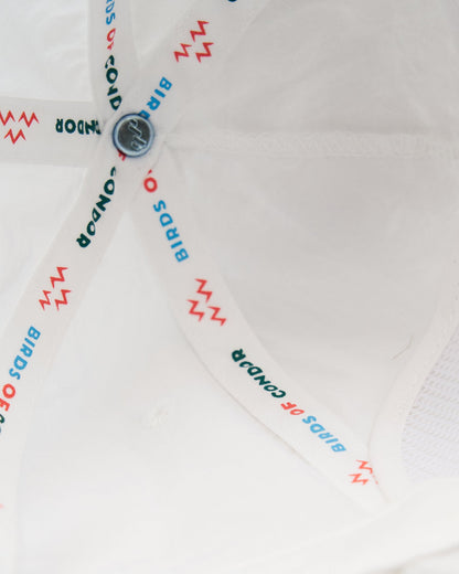Detail of the interior lining of a white cap, showing branded seam tape with text and lightning motifs.