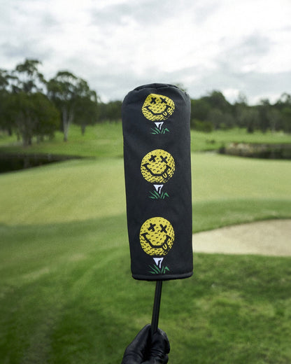 Black headcover featuring three stacked yellow smiley face golf ball graphics over green tees.