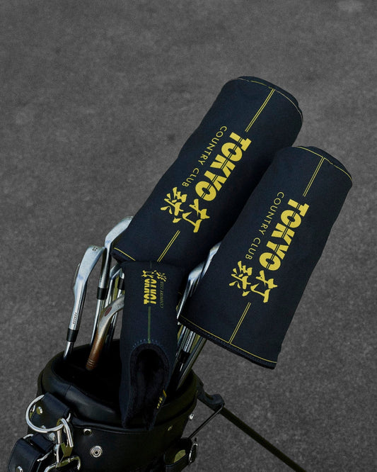 Two black headcovers with gold Tokyo Country Club text and line details in a golf bag.