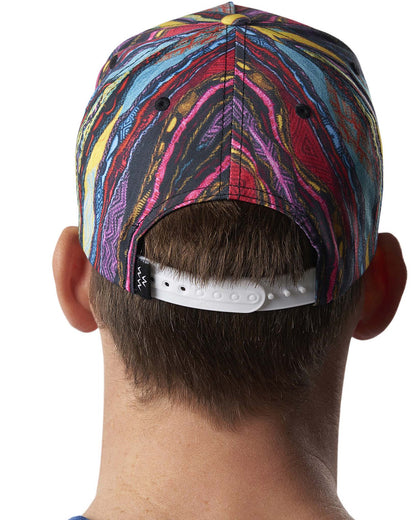 Back of a person wearing a multi-coloured Coogi print snapback hat with a white plastic adjustable strap.