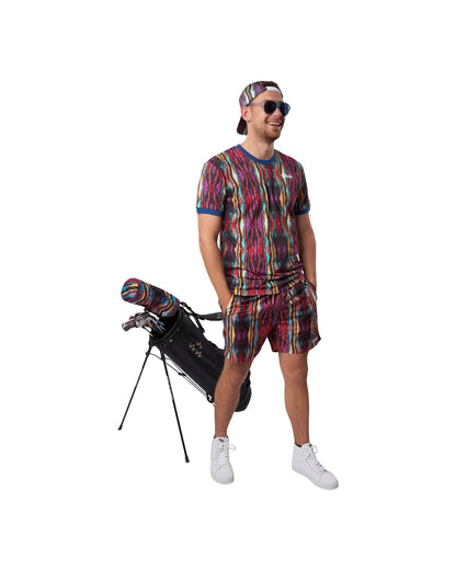 A man wearing a Coogi print cap, t-shirt and shorts, standing beside a black golf bag.