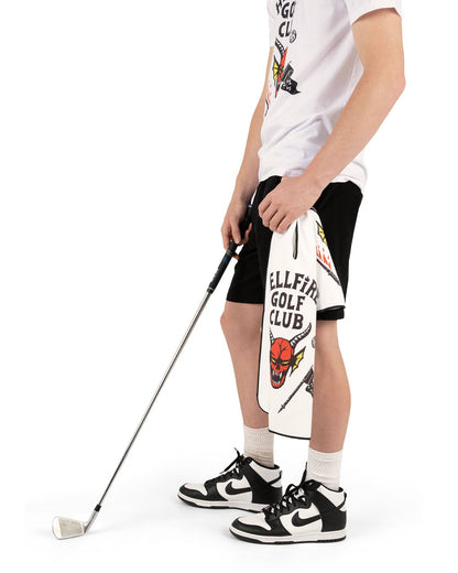 A man holding a white golf towel with a horned red devil head graphic and Hellfire Golf Club text.